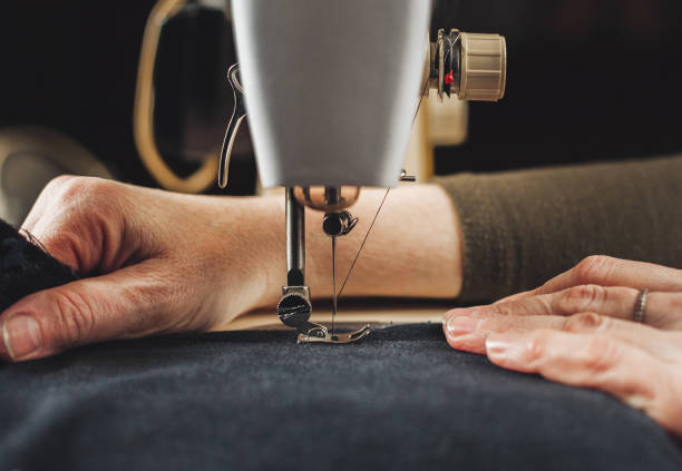 A close-up of a tailor's hands meticulously working on a suit jacket, showcasing the detailed craftsmanship at Tailors on Main LLC.